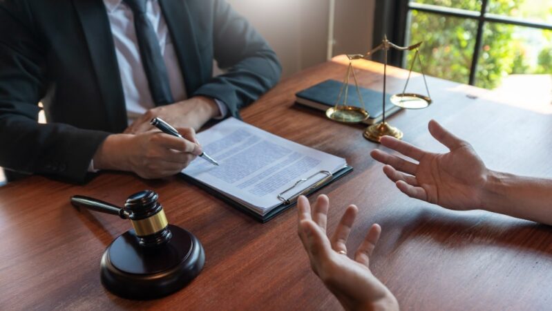 Un avocat signe un document pour un client dans un cabinet d'avocat.
