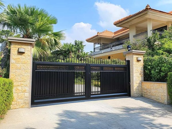 Élégant Portail chez AM Atlantique Ouverture S de style fer forgé noir, encadré par des piliers en pierre à l'entrée d'une villa