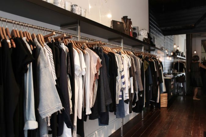Une allée de boutique chic avec des vêtements sur des cintres en bois, parfaite pour les grands événements shopping.
